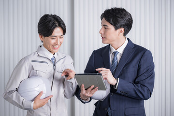 Men in construction management work clothes and suits checking materials at a general contractor or...