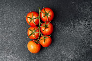 Fresh ripe tomatoes on a black textured surface ready for cooking