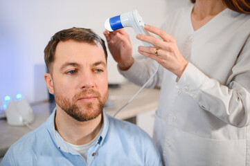 A trichologist examines the hair of a man who begins alopecia. Consultation with a dermatologist....