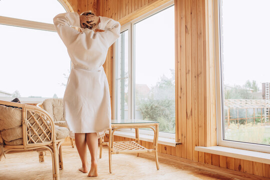 A young adult woman in a bathrobe on the veranda in the morning