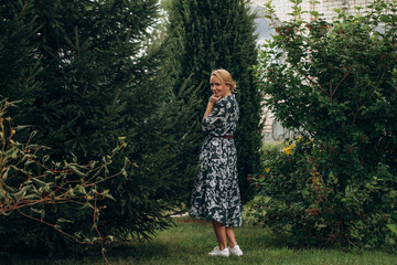 A young adult woman walks in the park among the fir trees