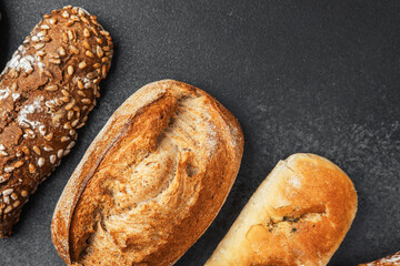 Delicious assortment of artisan breads on a dark surface with texture