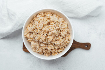 Warm bowl of oatmeal served on a wooden board in a cozy kitchen setting