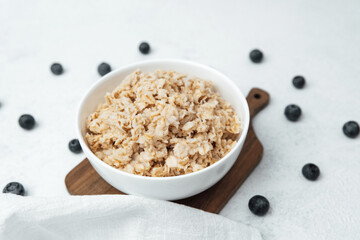 Oatmeal with blueberries served in a bowl on a wooden board