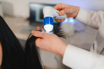 Doctor diagnoses the structure of the hair. Consultation with a trichologist