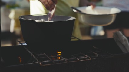 men cook food over a fire in a pot, recipe for a dish in a hike, put marinated juicy meat in a...