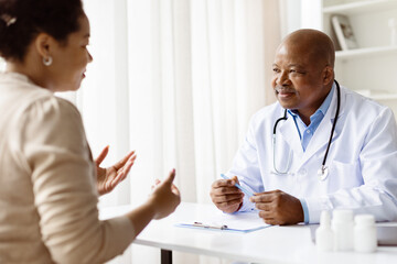 Doctor and patient have important conversation at clinic table. Pregnant woman shares concerns...