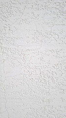 White stucco wall with cracked textured plaster surface. Close-up of aged building material.  Flat lay composition. background template with copy space.