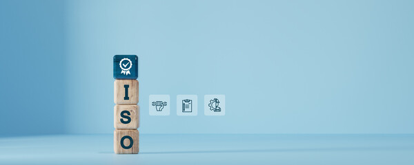 ISO standard certification concept with wooden blocks and icons related to quality control, process management, and tools on blue background. Ideal for industry and business themes.