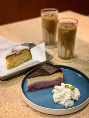 Delicious ube velvet cheesecake with whipped cream and a slice of moist cheesecake, served with refreshing iced lattes. Perfect dessert and coffee pairing.