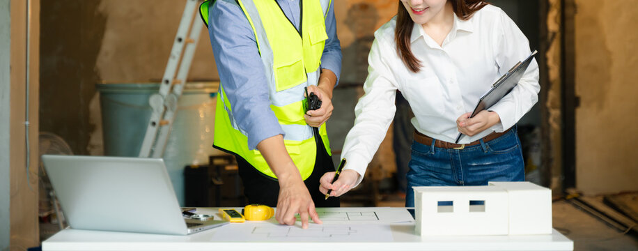 Creative architect projecting on the big drawings with architectural project at construction site at desk