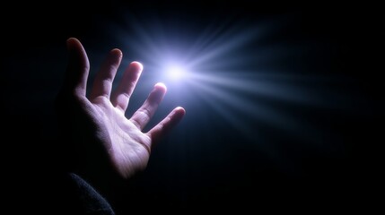 Hand reaching towards a bright light in a dark setting, symbolizing hope and inspiration in a moment of solitude