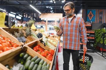Mature senor in the vegetables section of the supermarket