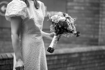 Black and white photo of a woman in a textured dress holding a wedding bouquet. Candid bridal photography 