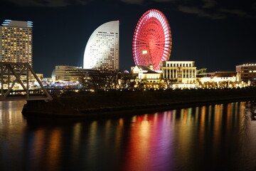 Illuminated Ferris Wheel and Buildings Reflect in Waters at Night, Urban Cityscape