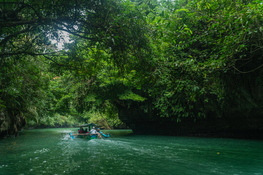 Wide shot of a boat crossing in the river of Green Canyon in Pangandaran, West Java, Indonesia. One of the most famous tourist attractions in West Java.
