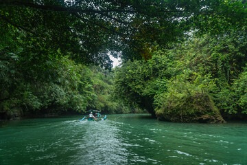 Wide shot of a boat crossing in the river of Green Canyon in Pangandaran, West Java, Indonesia. One of the most famous tourist attractions in West Java.