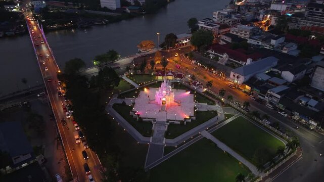 Surat Thani,Thailand-28 Jan 2025:Night aerial of Surat Thani City Pillar Shrine glowing, with city lights, Tapi River, and traffic illuminating the urban landscape of Thailand.