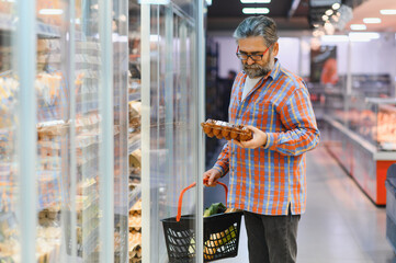 Male shopper chooses chicken eggs in a grocery supermarket