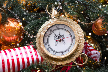 Golden retro clock on a Christmas tree. The clock hands show 12 o'clock. Beautiful background for...