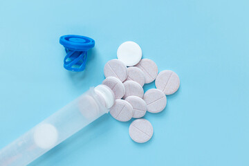 Opened pill tube with scattered round tablets and a blue cap. Concept of daily vitamins,...