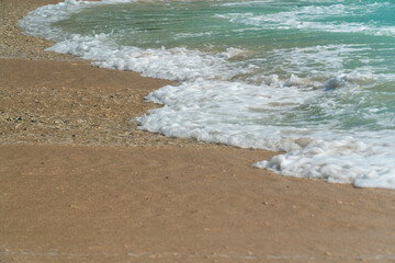 Closeup of sea waves crashing on beach sand.