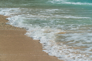 Closeup of sea waves crashing on beach sand.