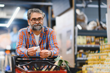 Holding check. Disappointed with prices. Senior Man customer is in the supermarket