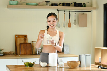 A woman is in a kitchen, smiling and preparing a drink. The kitchen is well-equipped with various...