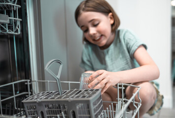 Child loads dishwasher. Everyday life concept,