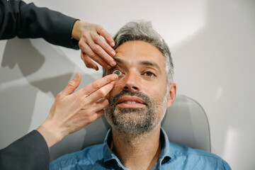 Optician assisting patient with contact lens in clinic