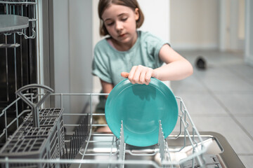 Child loads dishwasher. Everyday life concept,