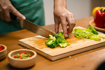Asian man's hands cutting bell peppers in the kitchen