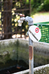 Old outdoor faucet with warning sign “Not for drinking water”.