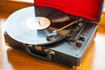 Vintage suitcase-style record player spinning vinyl record. Retro music in motion creating...