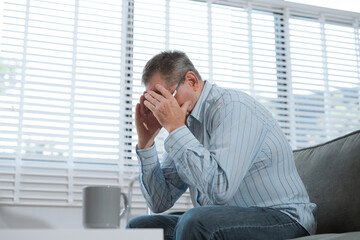 Senior man sitting in sofa, having depression, stress, irritability, and life problems.