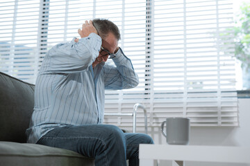 Senior man sitting in sofa, having depression, stress, irritability, and life problems.