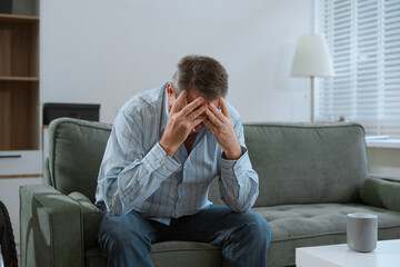 Senior man sitting in sofa, having depression, stress, irritability, and life problems.