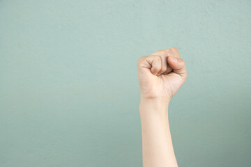 Raised clenched fist on soft green background symbolizing strength and determination