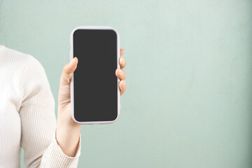 A woman hold and showing smartphone soft green background