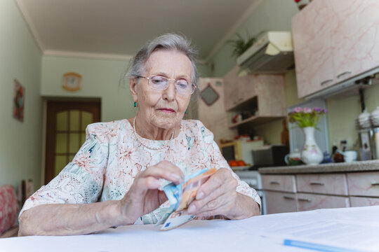 Senior woman counting money over home ownership paper