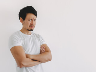 Asian man crossing arms and looking sideways with serious face in white shirt and clean background