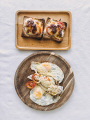 Top view of two breakfast plates with cinnamon rolls and eggs in white shirt and clean background
