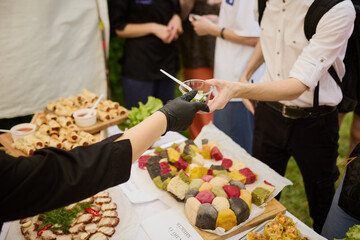 Hands of people taking food from a plastic plate during a banquet