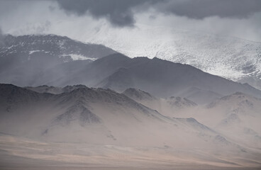 Panorama of mountain peaks and ridges with rocks and snow, with glaciers in the Tien Shan mountain system in the Pamirs in the highlands, cloudy weather