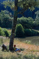 A woman rest under a tree on the lake shore