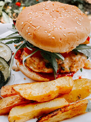 Delicious burger and crispy fries served with pickles in a outdoor setting