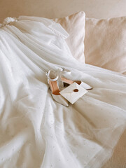 Elegant wedding dress and accessories displayed on a soft surface in a bright room