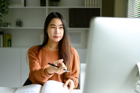 Young woman in a warm toned sweater working at a desktop computer in a home office