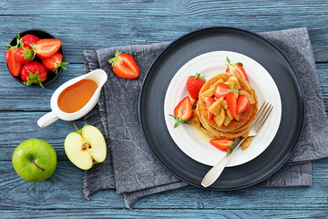 pancakes topped with apple slices and strawberries